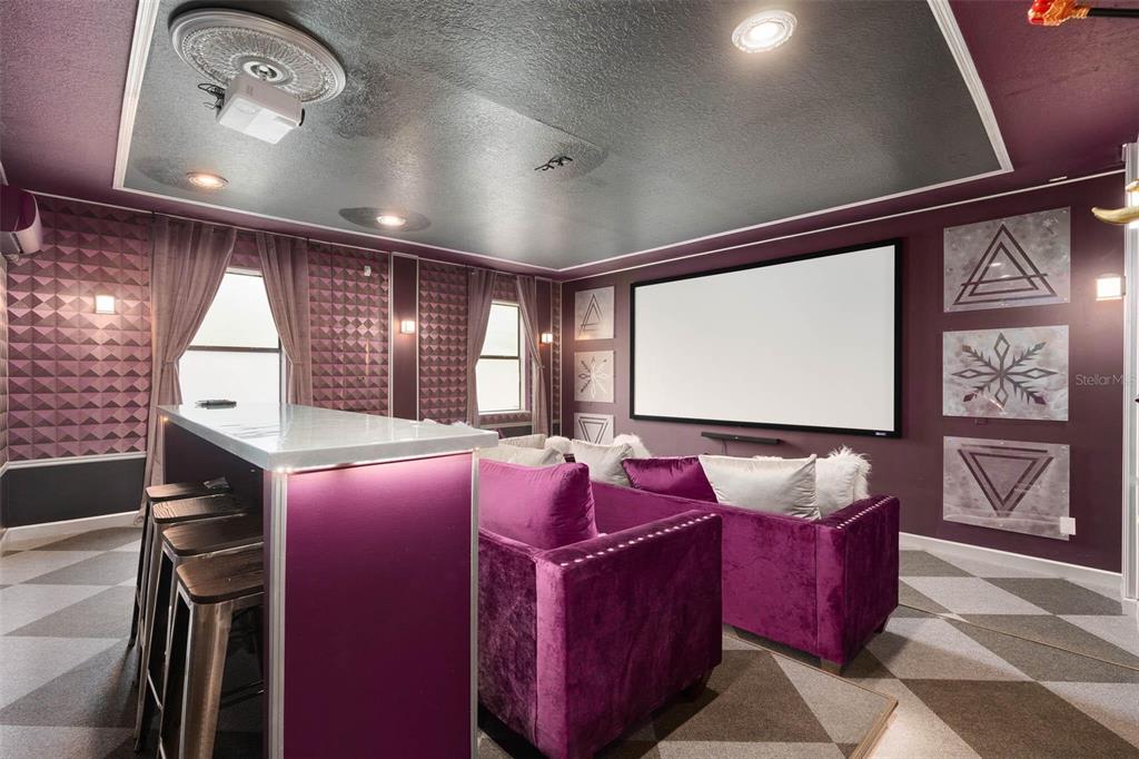 A home theater room features purple velvet sofas, a bar area, and a projector screen — 1403 MOON VALLEY DRIVE, DAVENPORT, FL