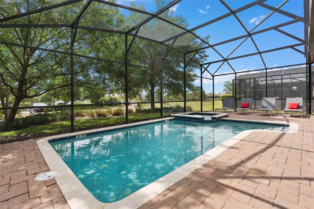 A screened-in swimming pool and hot tub sit on a brick paver patio outdoors — 1403 MOON VALLEY DRIVE, DAVENPORT, FL