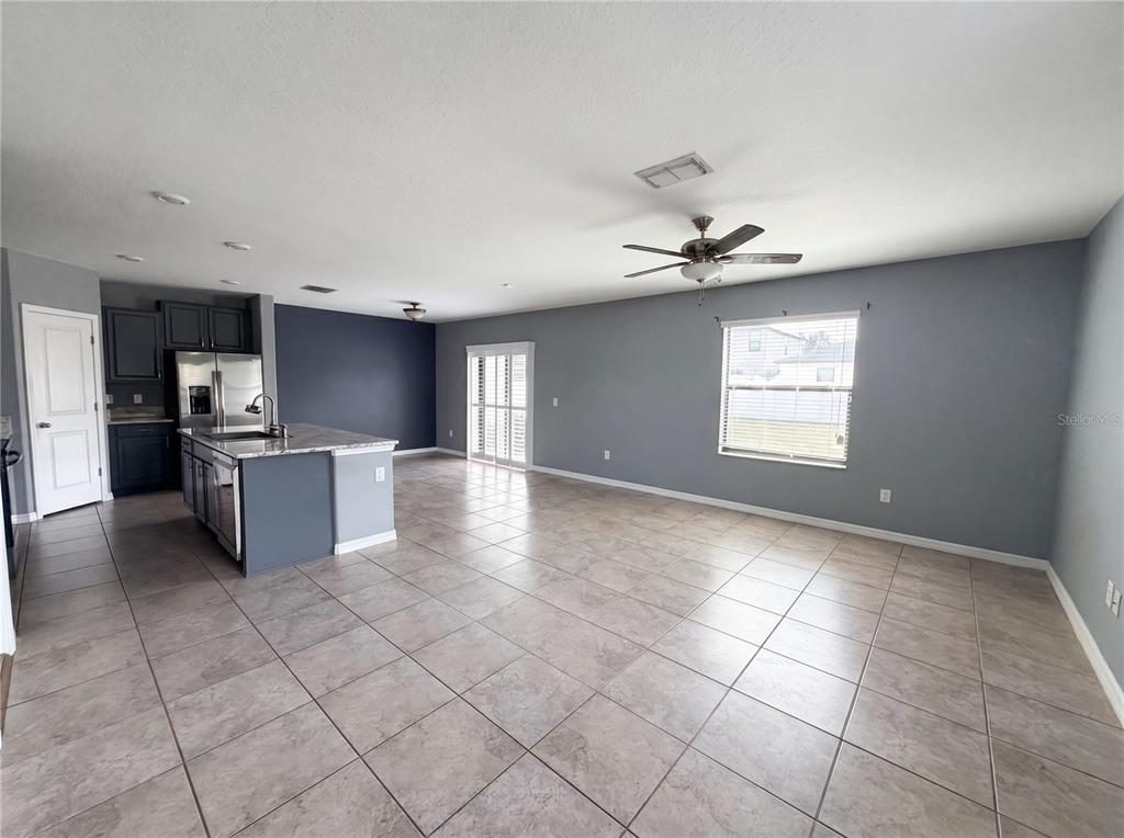 An open-concept kitchen and living area features tile flooring, gray walls, and a center island — 11126 HUDSON HILLS LANE, RIVERVIEW, FL