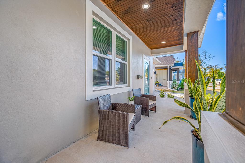 A covered front porch features wicker chairs, a wood-paneled ceiling, and a potted snake plant — 2144 43RD TERRACE N, ST PETERSBURG, FL
