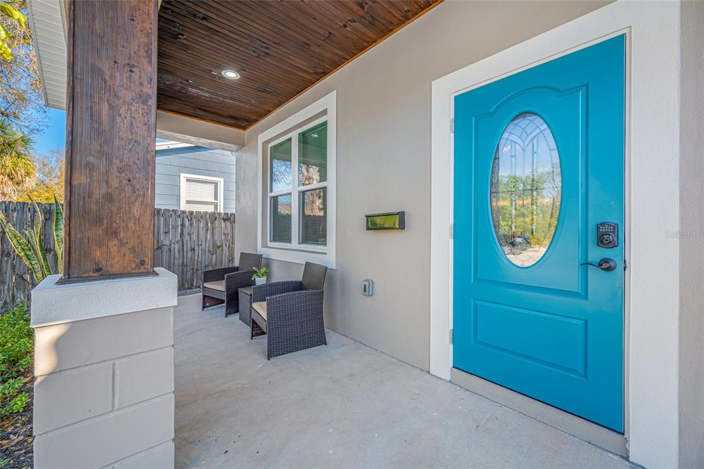 A covered front porch features a bright blue door, two wicker chairs, and wood ceiling — 2144 43RD TERRACE N, ST PETERSBURG, FL