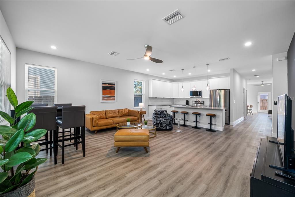 An open-concept living room and kitchen featuring light wood flooring and white cabinetry — 2144 43RD TERRACE N, ST PETERSBURG, FL