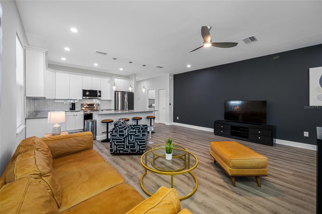 An open-concept living room and kitchen featuring a leather sofa, dark accent wall, and island — 2144 43RD TERRACE N, ST PETERSBURG, FL