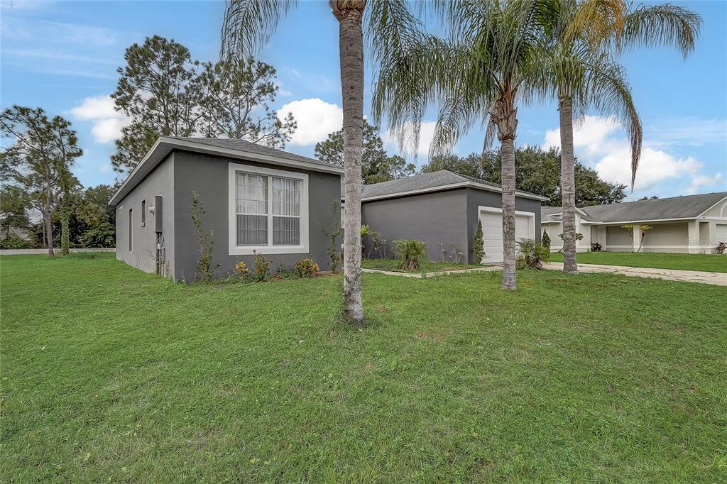 A gray single-story house with a two-car garage and palm trees in the front yard — 1023 EMBRUN COURT, KISSIMMEE, FL