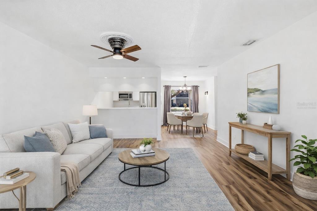 A living room with light wood floors, a gray sofa, and an open dining area — 1299 N SEAGULL POINT UNIT 163, CRYSTAL RIVER, FL