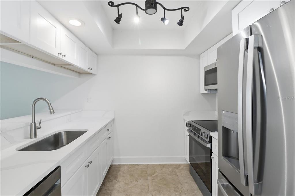 A galley kitchen features white cabinets, stainless steel appliances, and a sink with a faucet — 1299 N SEAGULL POINT UNIT 163, CRYSTAL RIVER, FL