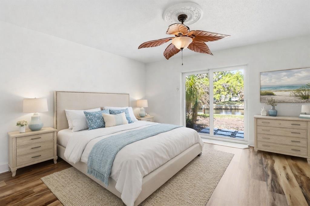 A bedroom features a bed with a light-colored headboard, a palm-leaf ceiling fan, and sliding doors — 1299 N SEAGULL POINT UNIT 163, CRYSTAL RIVER, FL