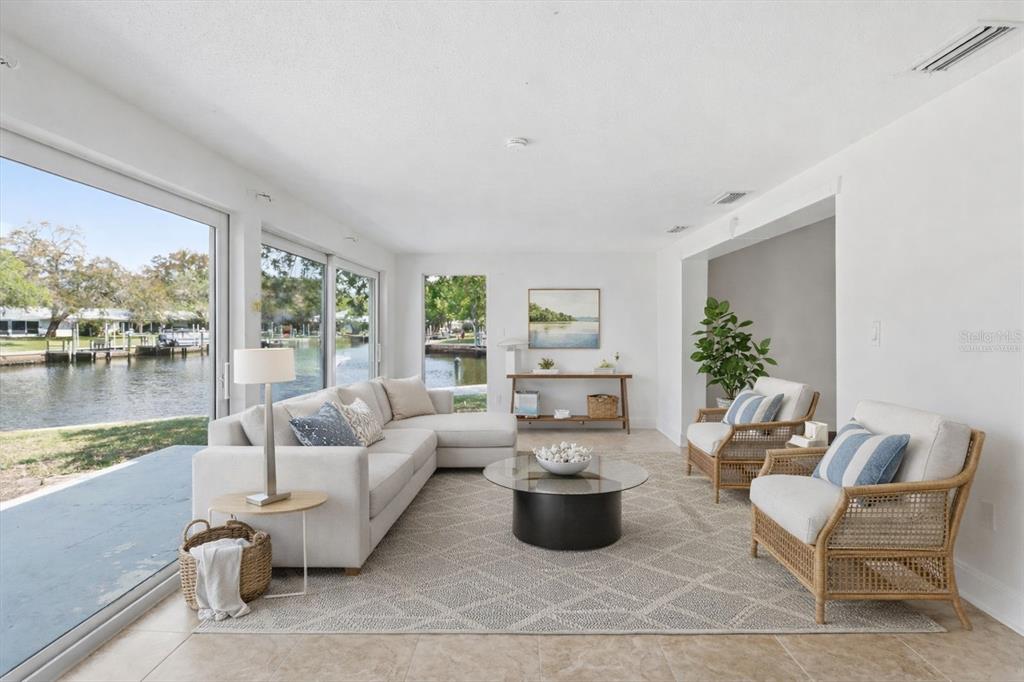 A bright living room features a sectional sofa, two rattan chairs, and large waterfront windows — 1299 N SEAGULL POINT UNIT 163, CRYSTAL RIVER, FL