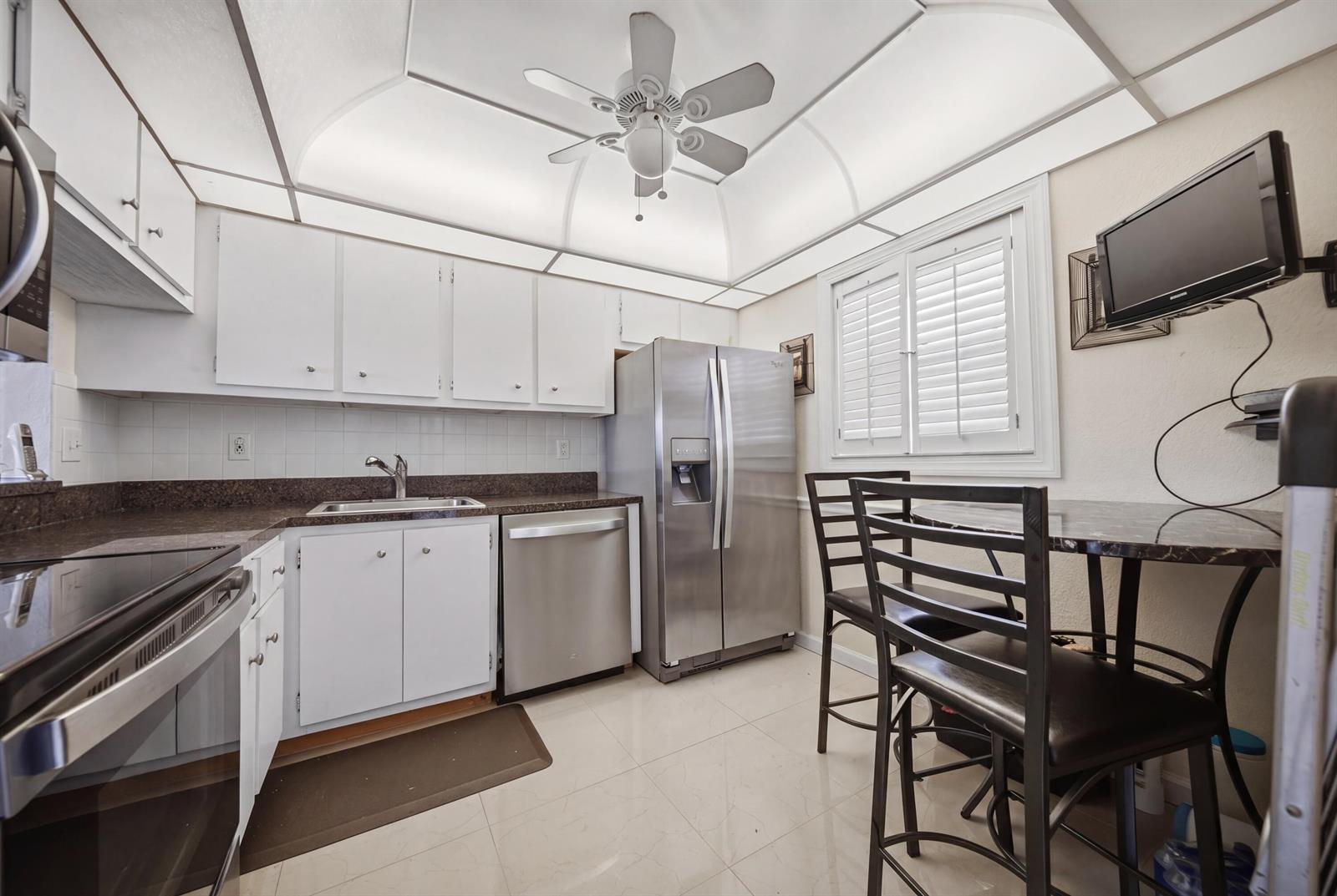 A kitchen with white cabinets, stainless steel appliances, a ceiling fan, and a dining area — 3040 Holiday Springs Boulevard # 212, Margate FL 33063, MARGATE, FL