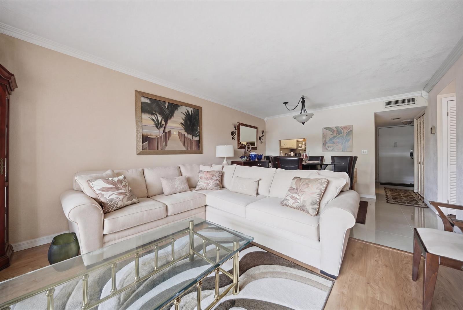 A living room features a beige sectional sofa, a glass coffee table, and wood flooring — 3040 Holiday Springs Boulevard # 212, Margate FL 33063, MARGATE, FL