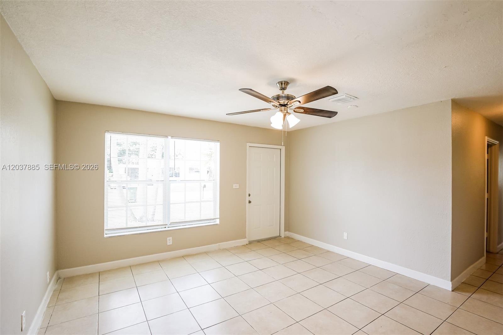 An empty room features beige walls, light-colored tile flooring, a ceiling fan, and a window — 5980 NW 24th Ct, Margate FL 33063, MARGATE, FL