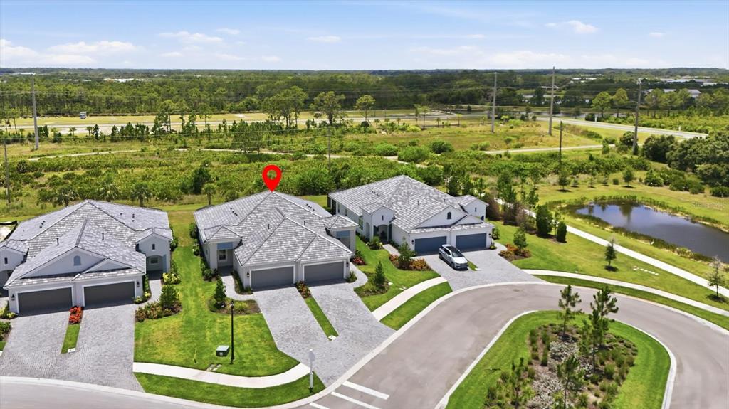 An aerial view shows three suburban houses with gray tile roofs and paved driveways — 2321 BLUE MAHOE LANE, SARASOTA, FL