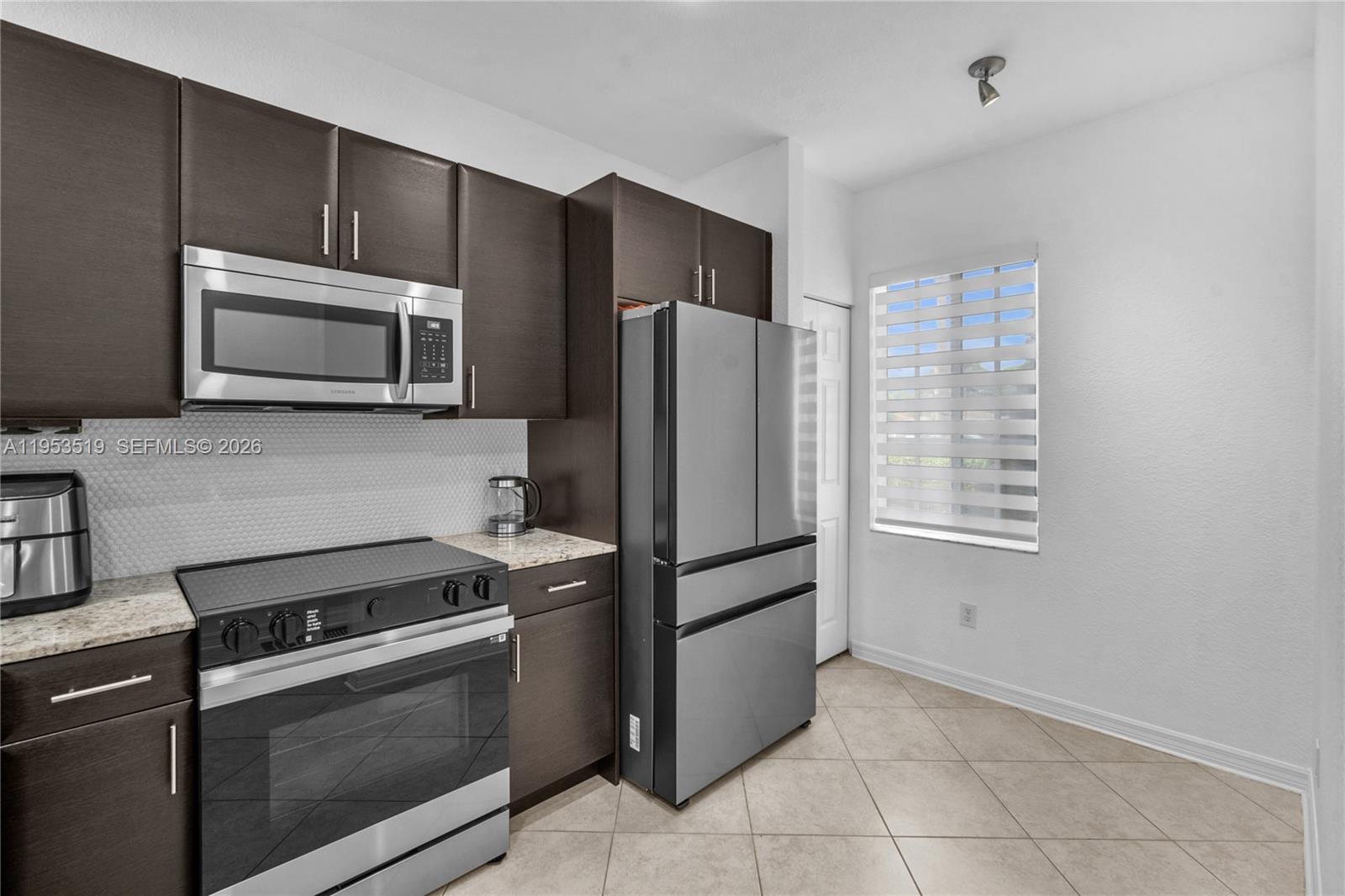 A kitchen features dark wood cabinets, stainless steel appliances, and light-colored tile flooring — 121 NW 2nd Ave # 4, Hallandale Beach FL 33009, HALLANDALE BEACH, FL