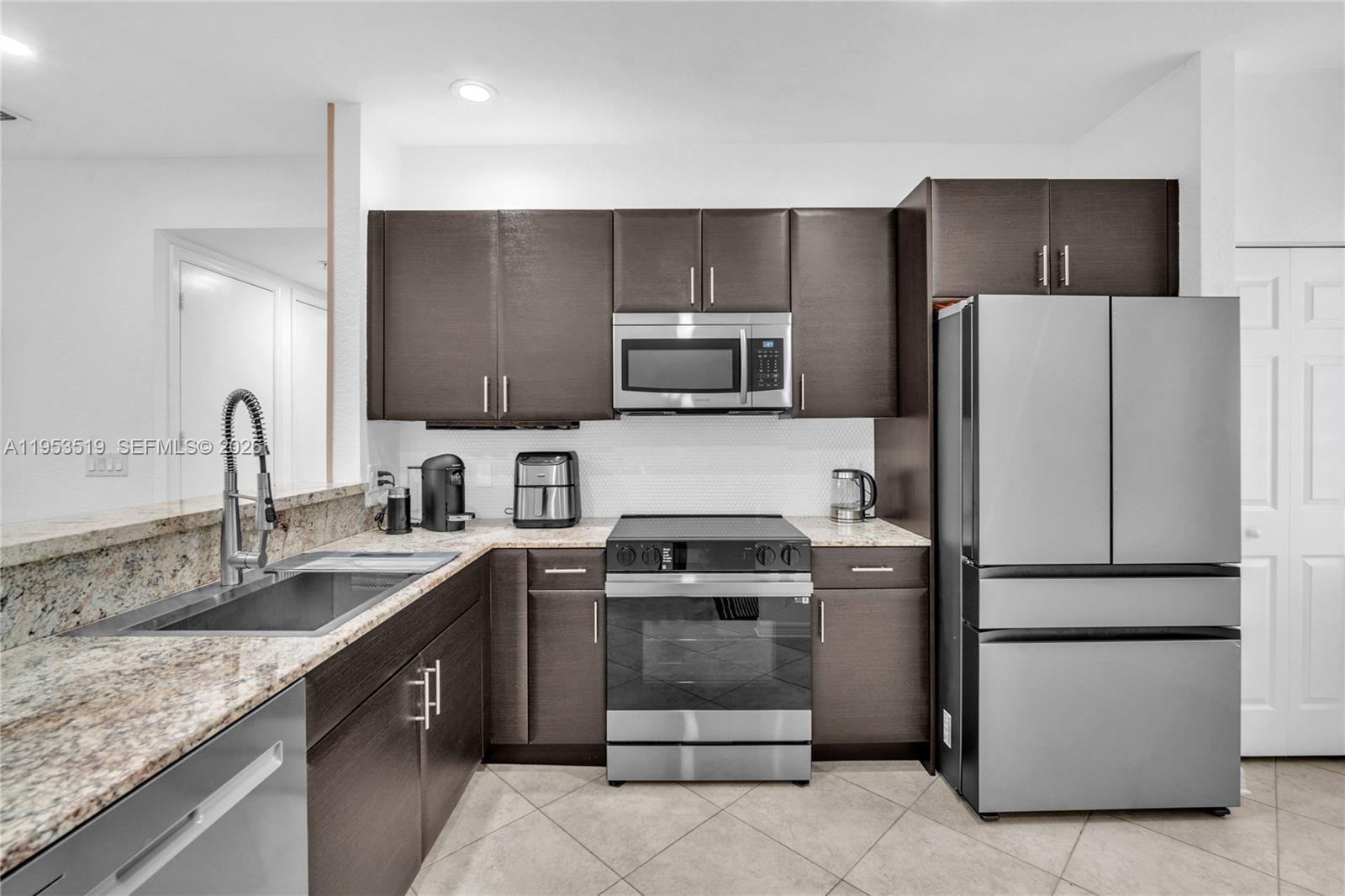 A kitchen features dark wood cabinets, stainless steel appliances, and granite countertops — 121 NW 2nd Ave # 4, Hallandale Beach FL 33009, HALLANDALE BEACH, FL