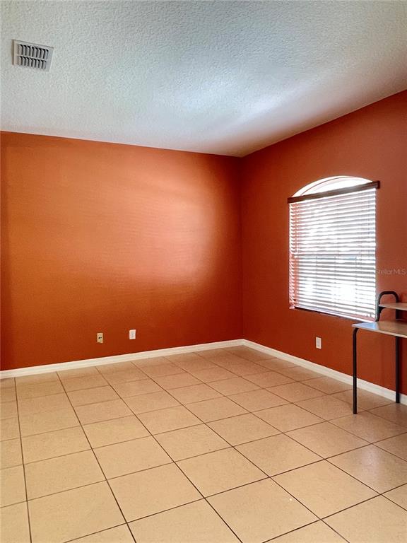 An empty room with orange walls, tile flooring, and a window with blinds — 12810 BOGGY VIEW DR, ORLANDO, FL