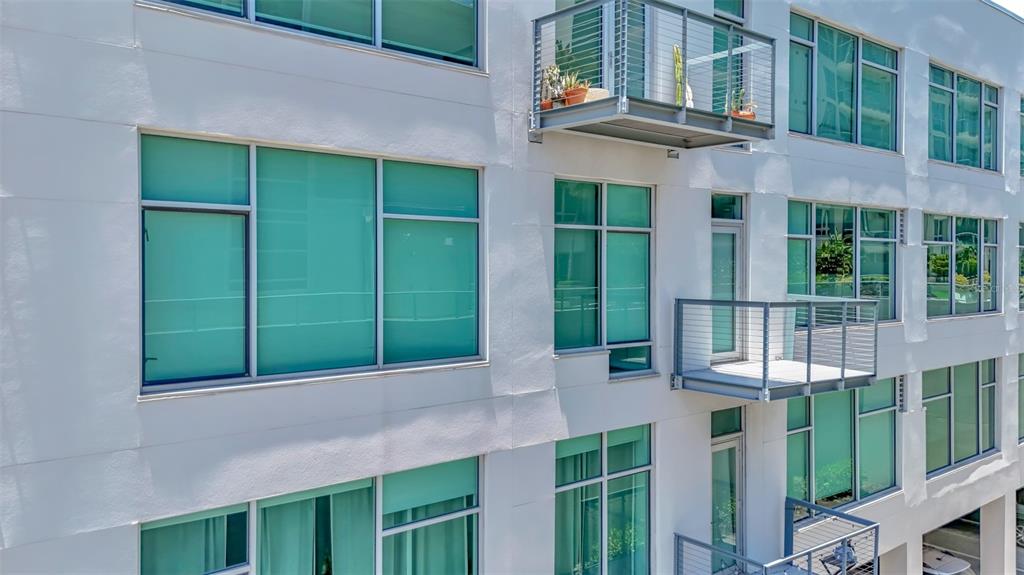 Exterior view of a multi-story modern apartment building featuring balconies and large glass windows — 101 N 12TH STREET UNIT 302, TAMPA, FL