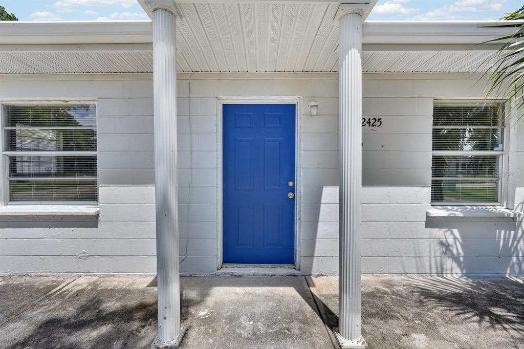 A blue front door is centered between two white columns on a concrete porch — 2425 ANASTASIA DRIVE, SOUTH DAYTONA, FL