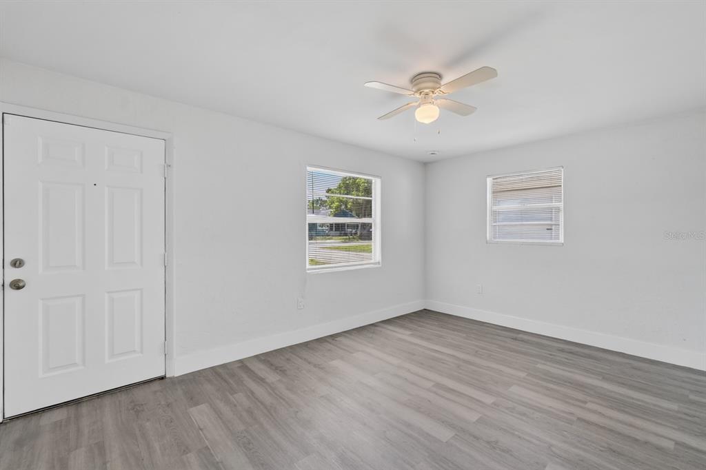 An empty room with white walls, gray wood-look flooring, a ceiling fan, and two windows — 2425 ANASTASIA DRIVE, SOUTH DAYTONA, FL