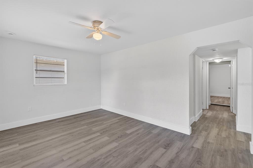 A room with white walls, gray wood-look flooring, a ceiling fan, and an arched doorway — 2425 ANASTASIA DRIVE, SOUTH DAYTONA, FL