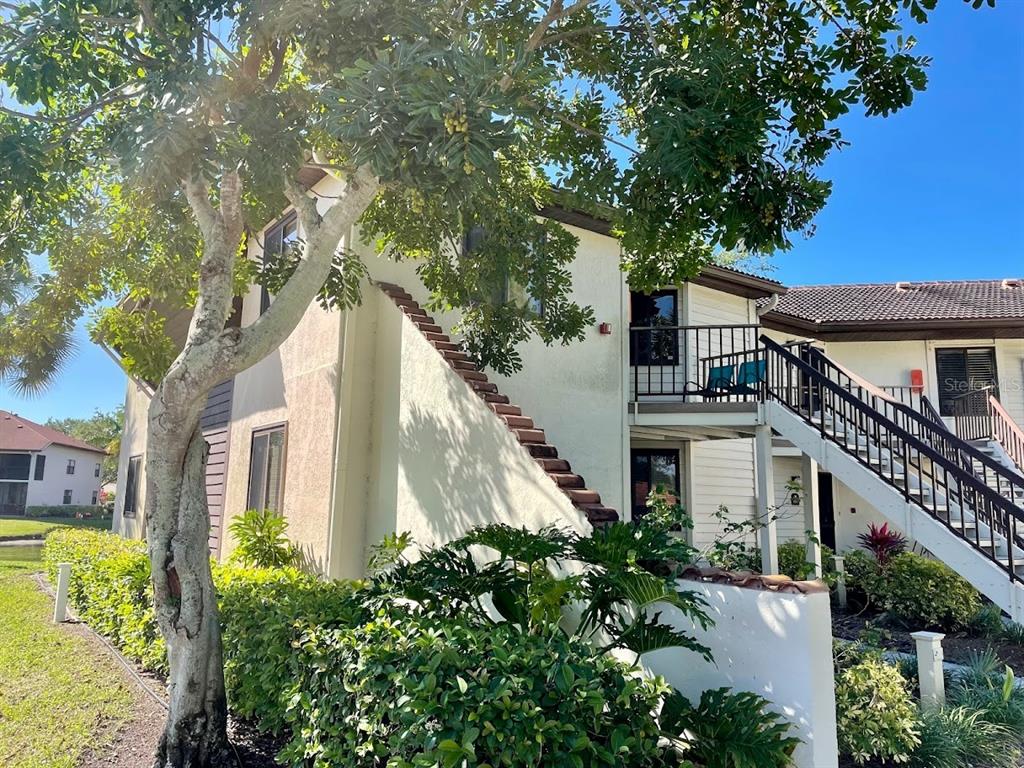 A two-story building exterior features a staircase leading to an upper-level balcony and landscaping — 4503 46TH AVENUE W, BRADENTON, FL