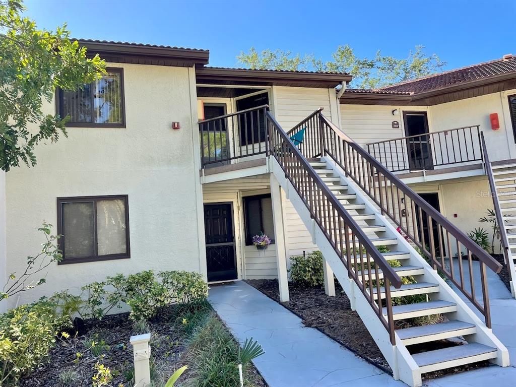 A two-story apartment building exterior features a central staircase leading to an upper-level balcony — 4503 46TH AVENUE W, BRADENTON, FL