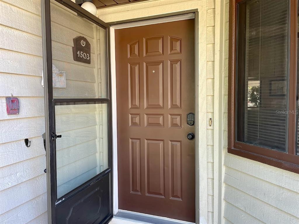 A brown front door with a screen door and house number 4503 on the siding — 4503 46TH AVENUE W, BRADENTON, FL
