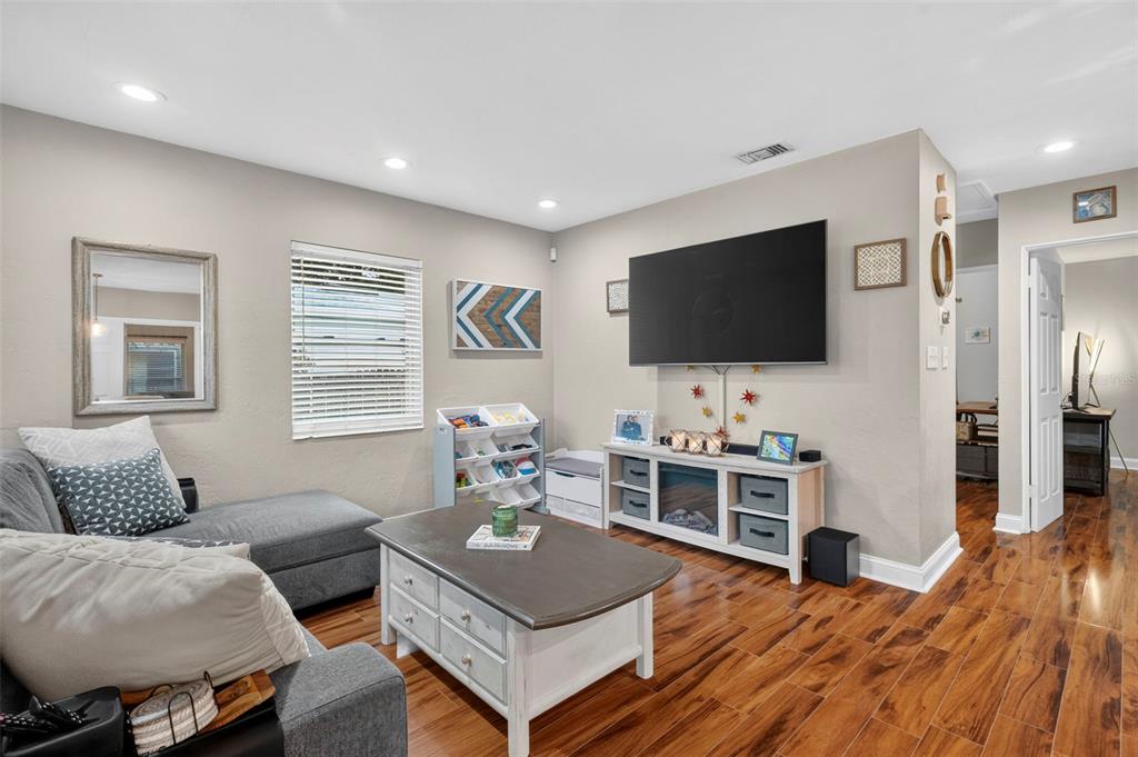 A living room features a grey sectional sofa, a coffee table, and a wall-mounted television — 1226 49TH AVENUE N, ST PETERSBURG, FL