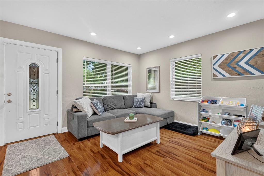 A living room features a gray sectional sofa, a white coffee table, and wood-look flooring — 1226 49TH AVENUE N, ST PETERSBURG, FL