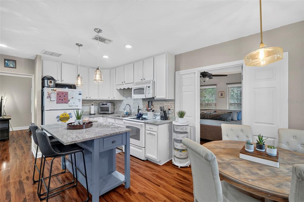 A kitchen features white cabinets, a blue island, granite countertops, and an adjacent dining area — 1226 49TH AVENUE N, ST PETERSBURG, FL