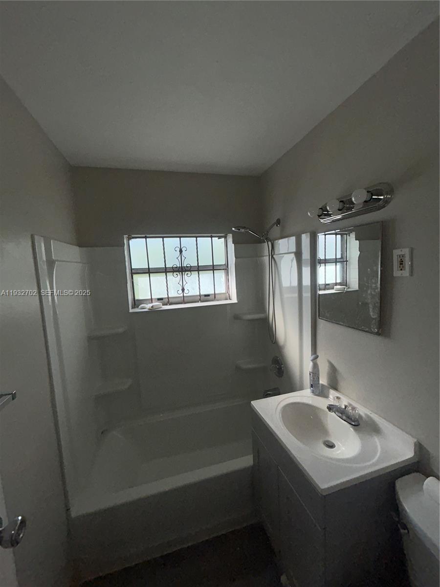 A bathroom features a white tub-shower combination, a vanity with a sink, and a window — 1180 NW 64th St # B, Miami FL 33150, MIAMI, FL