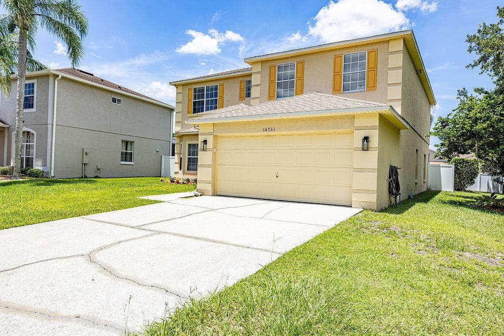 A two-story suburban house with a beige stucco exterior and a two-car garage — 14733 HARTFORD RUN DRIVE, ORLANDO, FL