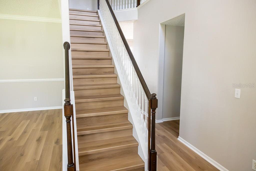 A wooden staircase with white balusters and a dark handrail leads to an upper landing — 14733 HARTFORD RUN DRIVE, ORLANDO, FL
