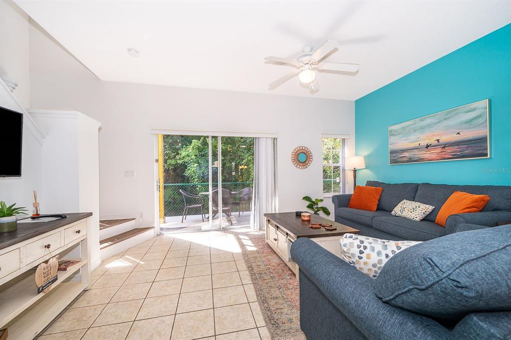 A living room features a blue accent wall, tile flooring, and a sliding glass door — 1113 PARK RIDGE CIRCLE, KISSIMMEE, FL