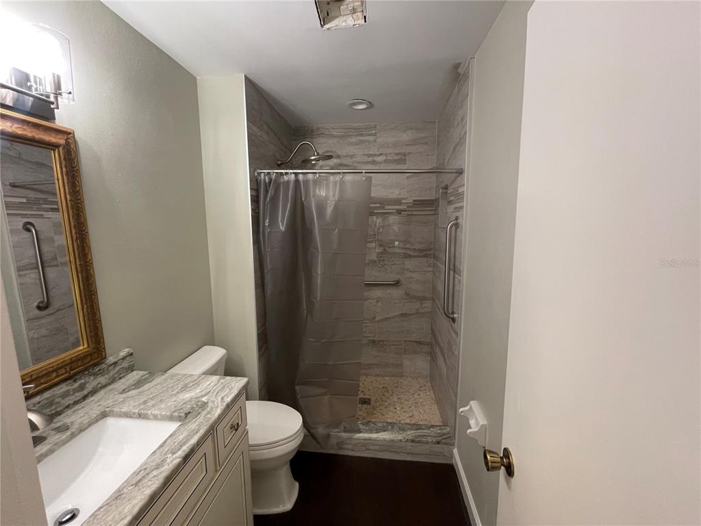 A bathroom features a vanity with a stone countertop, a toilet, and a tiled shower — 6366 71ST STREET N, PINELLAS PARK, FL