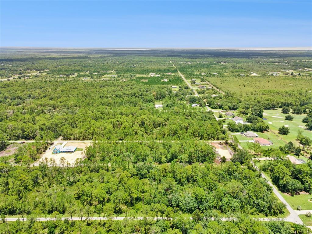 An aerial view shows a house under construction surrounded by dense woods and nearby homes — 0 PANDORA DR, INDIAN LAKE ESTATES, FL