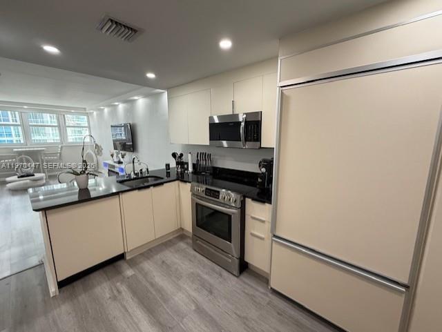 A modern kitchen features light-colored cabinetry, stainless steel appliances, and gray wood-look flooring — 10275 Collins Ave # 1505, Bal Harbour FL 33154, BAL HARBOUR, FL