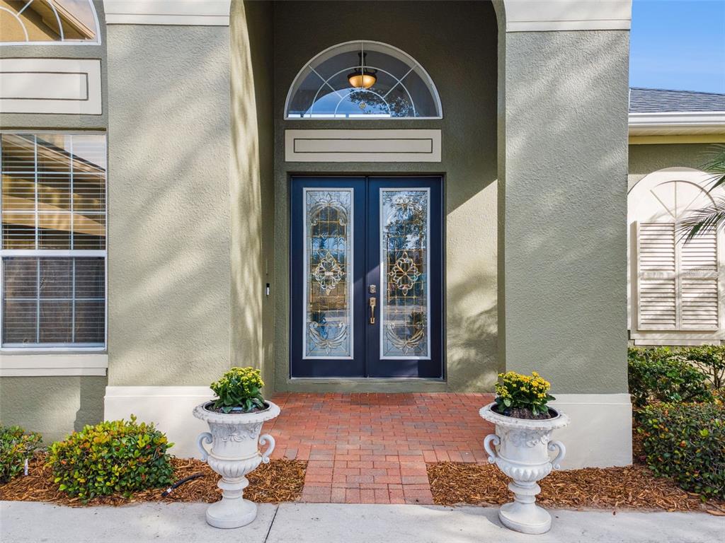 A front entrance features double glass-paneled doors, a semi-circular transom window, and two decorative planters — 3643 PEACEFUL VALLEY DRIVE, CLERMONT, FL