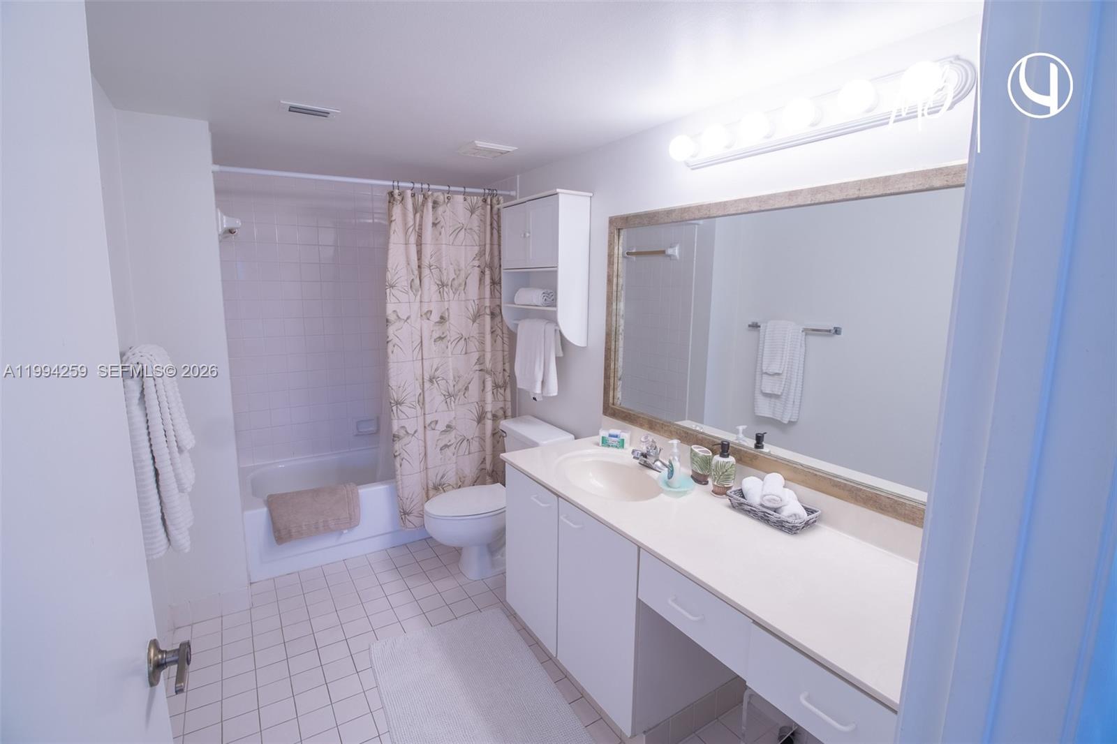 A bathroom features a white vanity, a large mirror, and a shower-tub combination — SUNNY ISLES BEACH, FL