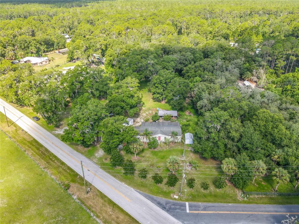 An aerial view shows a house surrounded by dense trees near a paved road — 1116 EMPORIA ROAD, PIERSON, FL