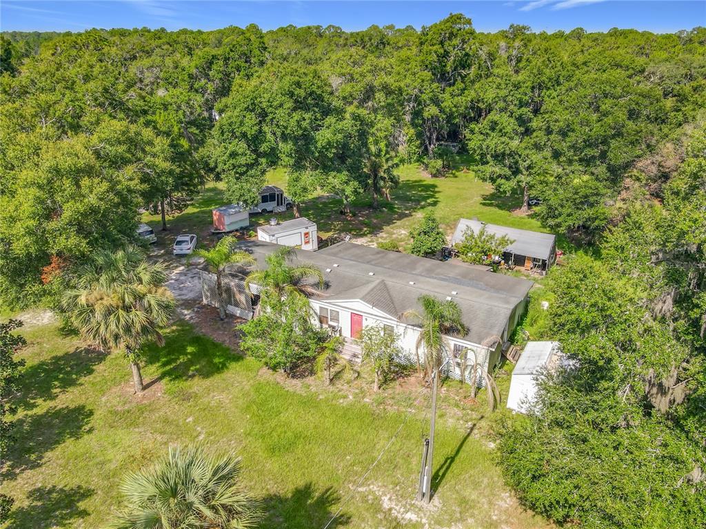 An aerial view shows a single-story house surrounded by trees with several trailers parked nearby — 1116 EMPORIA ROAD, PIERSON, FL