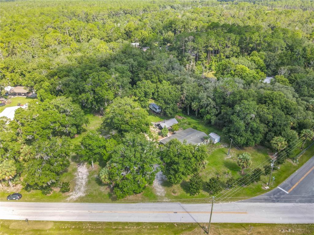 An aerial view shows a house and a trailer situated on a wooded lot — 1116 EMPORIA ROAD, PIERSON, FL