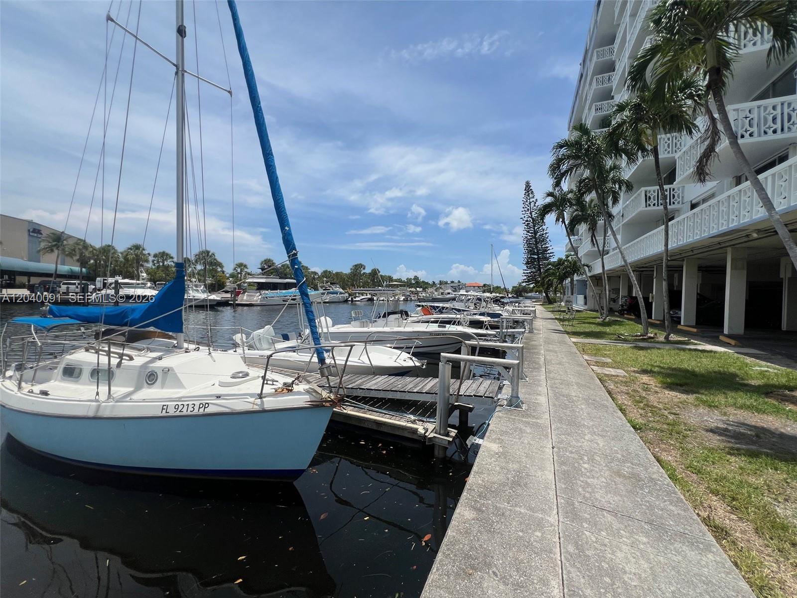 A sailboat is docked at a pier next to a multi-story residential building — 13155 Ixora Ct # 703, North Miami FL 33181, NORTH MIAMI, FL