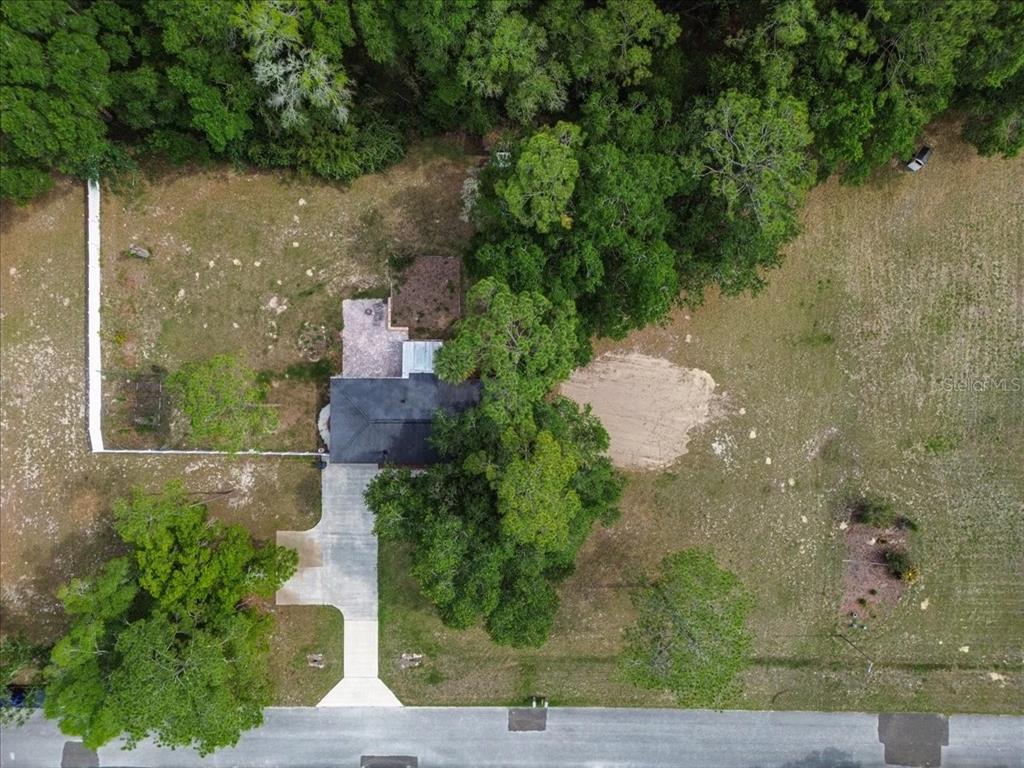 An aerial view shows a house with a concrete driveway surrounded by trees and grass — 10803 SW 92ND PLACE, GAINESVILLE, FL