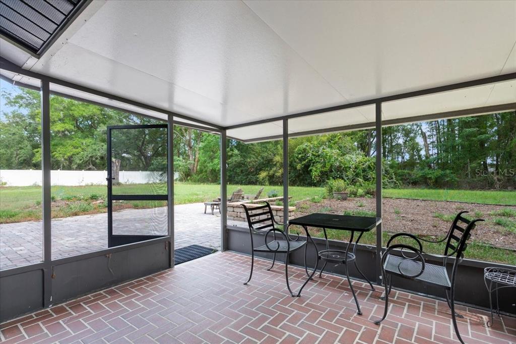 A screened-in porch with a brick floor, metal furniture, and a view of the backyard — 10803 SW 92ND PLACE, GAINESVILLE, FL