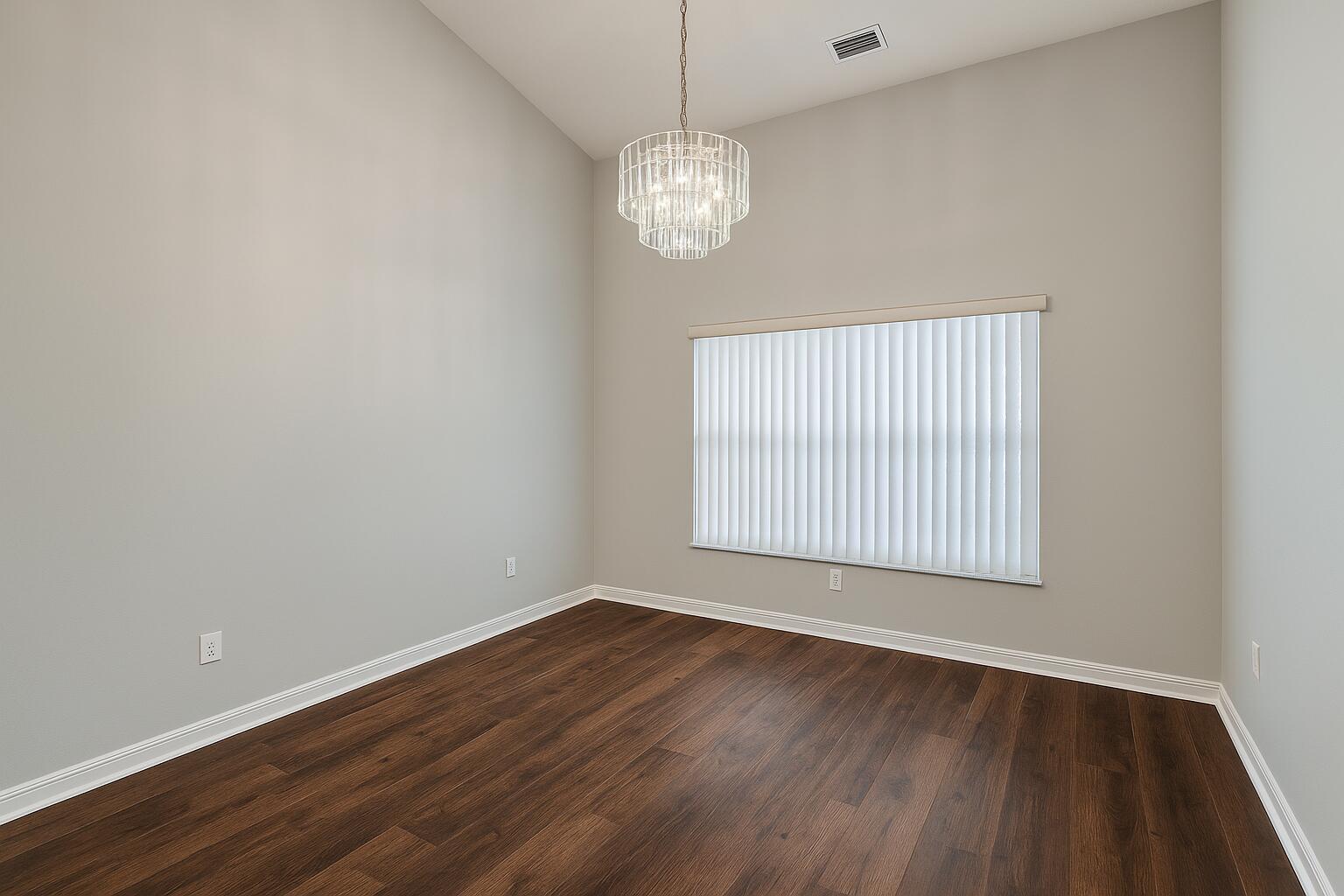 An empty room with dark wood flooring, light gray walls, and a crystal chandelier — 1120 Fairfield Lane, Sebastian FL 32958, SEBASTIAN, FL