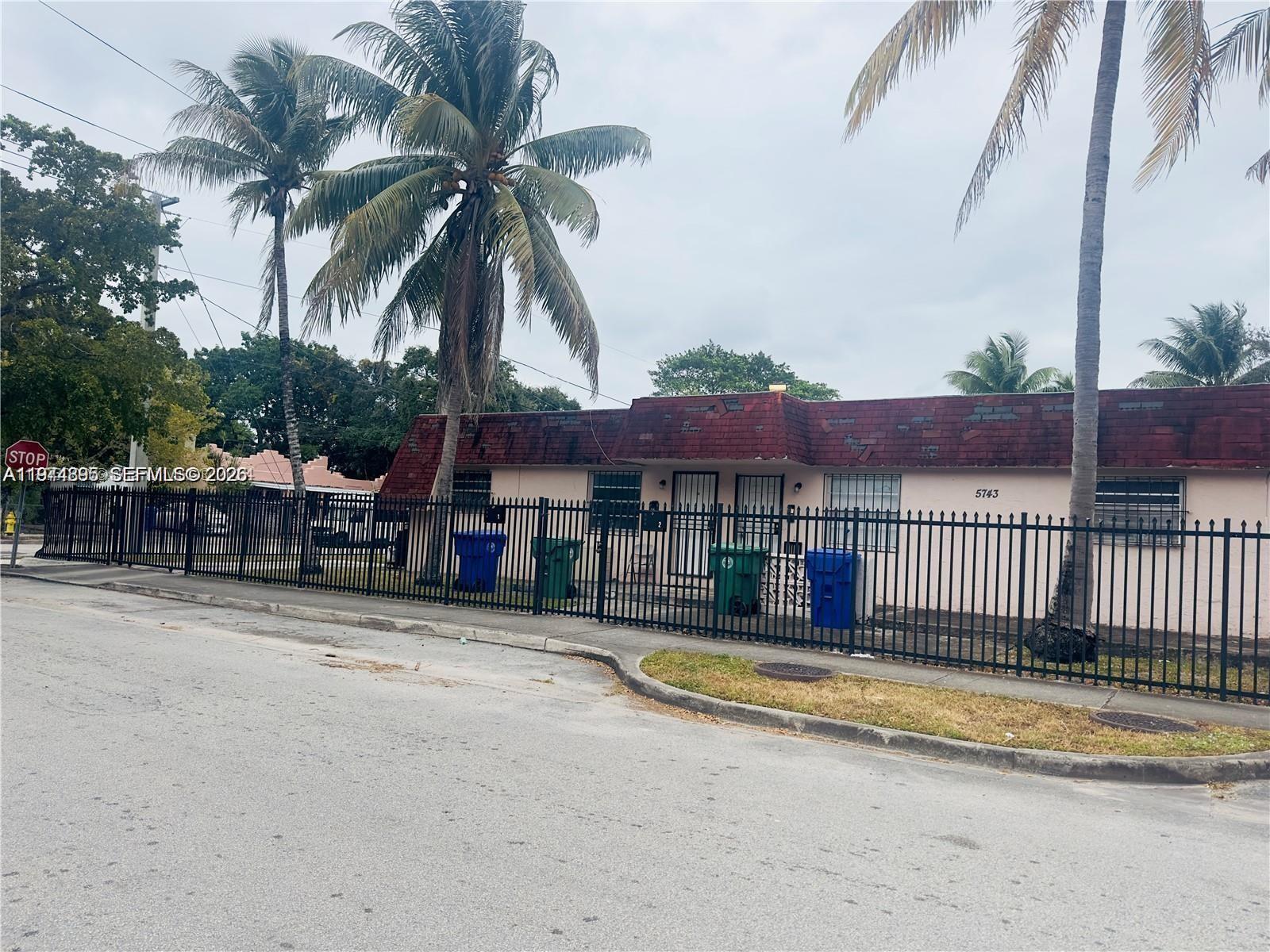 A single-story house with a red shingled roof is enclosed by a black metal fence — 5743 NW 3rd Ave, Miami FL 33127, MIAMI, FL