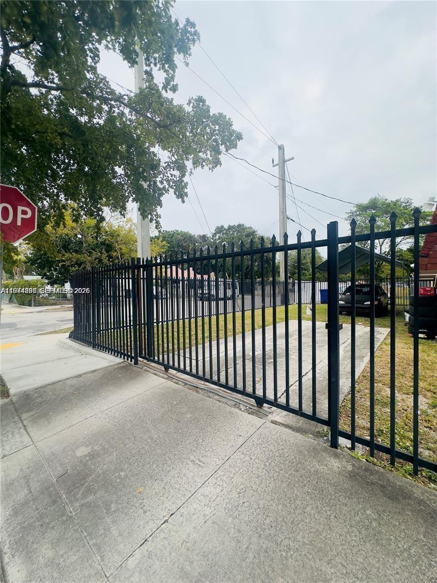 A black metal fence with a sliding gate encloses a concrete driveway and yard — 5743 NW 3rd Ave, Miami FL 33127, MIAMI, FL