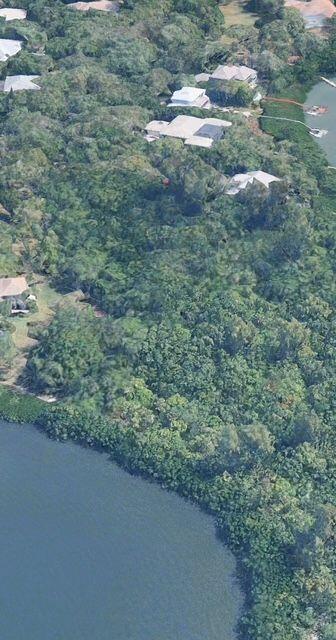 An aerial view shows several houses nestled within a dense forest bordering a body of water — Lot 12 Riverview Court, Vero Beach FL 32963, VERO BEACH, FL