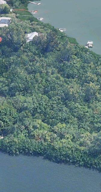 An aerial view shows a dense forest bordering a body of water with several docks — Lot 12 Riverview Court, Vero Beach FL 32963, VERO BEACH, FL