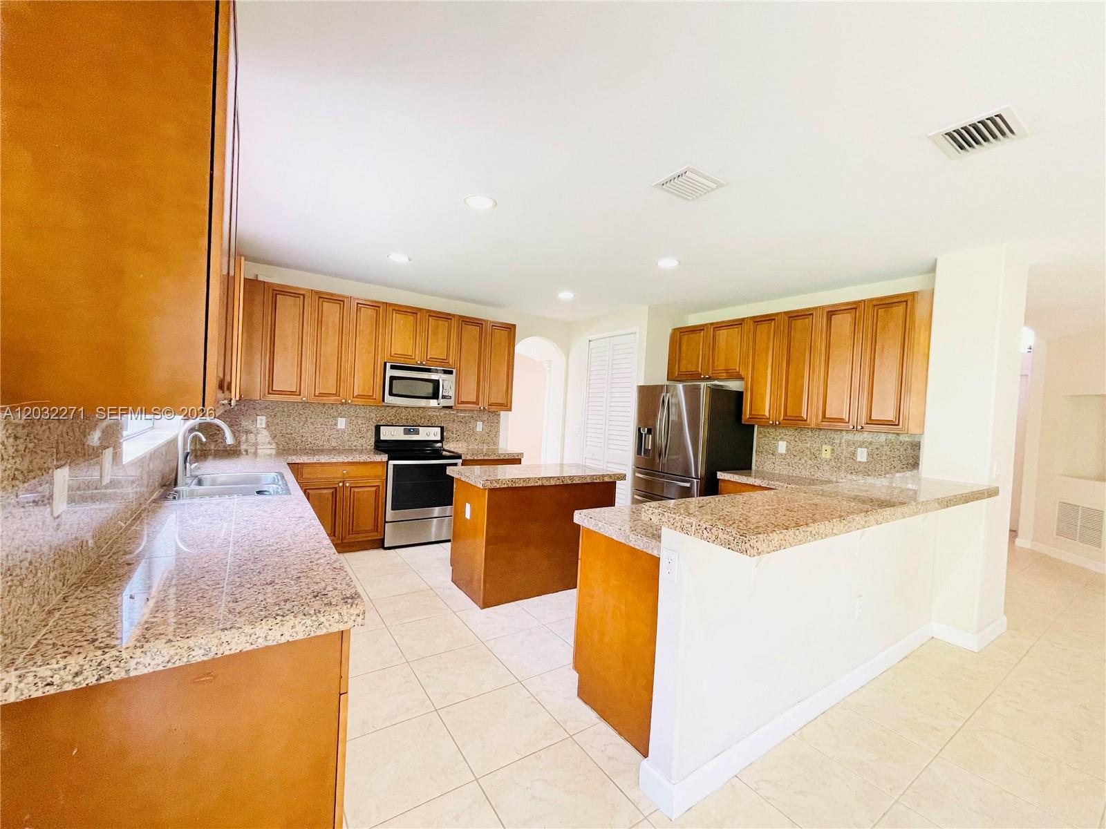 A kitchen features wood cabinets, granite countertops, stainless steel appliances, and a central island — 7427 SW 189th St, Cutler Bay FL 33157, CUTLER BAY, FL